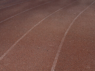 Close-up texture of rubberized running track on stadium with marked lanes.