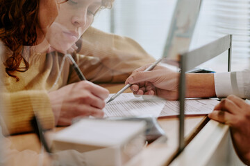 Two individuals closely working together, reviewing and signing important documents, creating an...