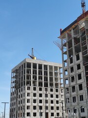 Fototapeta premium Skyscrapers being built with cranes in the background