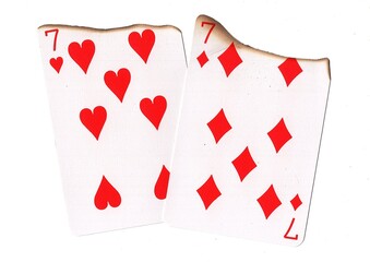 A pair of partially burnt playing cards of the same value on a white background.