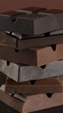 Milk and dark chocolate bars on a brown background. Close-up footage on the rotating table.