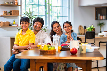 Happy Indian parents and kids share breakfast at the dining table, enjoying quality family time
