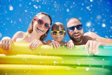 Happy family playing in waterpark. People having fun on summer vacation. Family jumping into swimming pool with splashes of water.