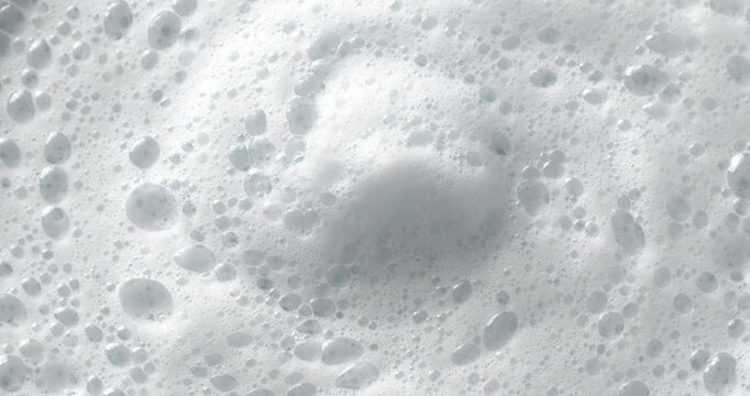 Foam bubbles background. Moving Soap foam popping bubble. Close-up footage on the rotating table.
