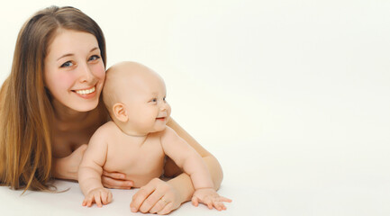 Portrait of happy smiling young mother playing with cute baby lying together on white background
