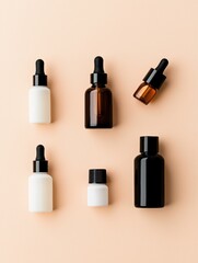 Collection of six small glass dropper bottles of different sizes and shapes arranged in a row on a light peach-colored background.