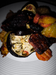 Roasted eggplant, potatoes, carrots, and seitan on white plate, spring seasonal dish