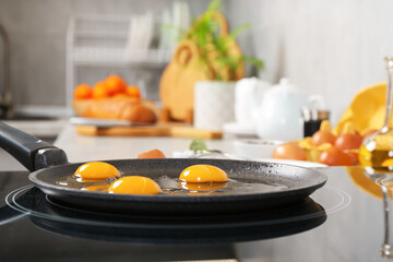 Cooking tasty eggs on frying pan in kitchen, closeup