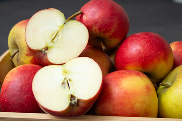 Fresh small organic red apples in a wooden crate on grey table background