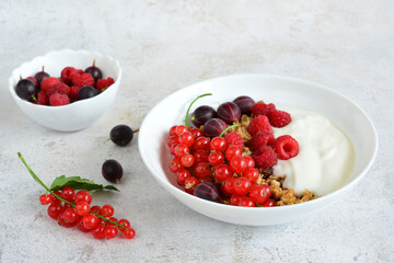 Healthy breakfast with red currants, raspberries and gooseberries with yogurt and granola