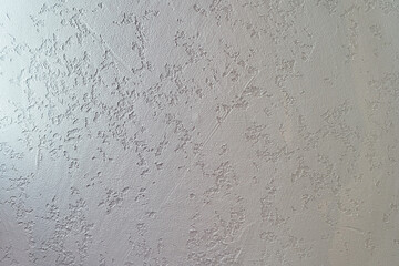 Uneven background with the texture of decorative plaster painted in white concrete wall. Rough wall with space for copying. High quality photo