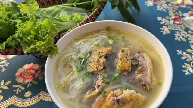 Vietnamese Chicken Soup warm bowl of Vietnamese chicken noodle soup with lime and fresh herbs being garnished