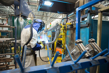 Men at work. Young man wearing protective stuff, working with tools and machinery in a car factory