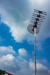 outdoor tv antenna for digital broadcasting with clouds and clear blue sky in the background