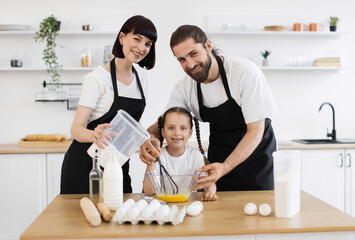 Caucasian family cooking in kitchen, adults and child enjoying family activity preparing food.