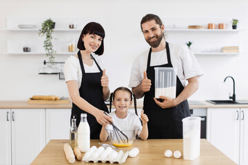 Caucasian family with parents and young daughter cooking together, showcasing teamwork and joy....