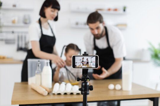 Caucasian parents and child baking together while filming online cooking video during family activity