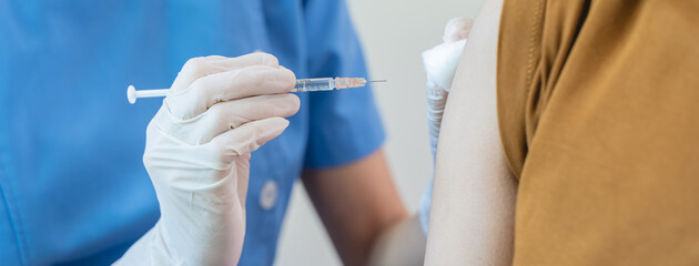 People getting a vaccination to prevent pandemic concept. Woman in medical face mask  receiving a dose of immunization coronavirus vaccine from a nurse at the medical center hospital