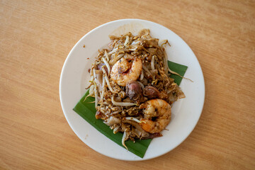 A plate of char koay teow or stir fried flat rice noodle dish made popular in Penang Malaysia. It is smoky flavor, sweet and savory with prawns, cockles and sausages.