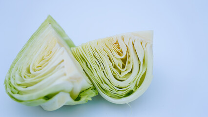 A cabbage cut in half, showcasing its fresh green leaves and internal layers, isolated on a plain white background
