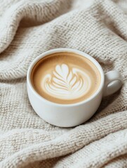 Close-up of a white coffee cup with a handle on a beige knitted blanket.