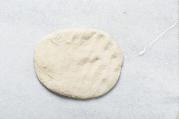 Overhead view of steamed bun dough being folded, top view of mantou dough being rolled out, process of making steamed milk buns