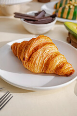 Golden Flaky Croissant on White Plate – Fresh Pastry Photography
