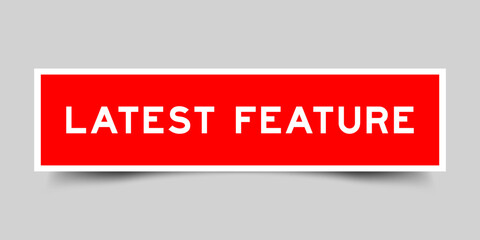 Red color square shape sticker label with word latest feature on gray background