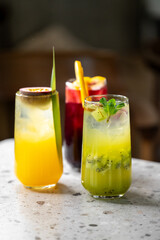 Three vibrant cocktails are displayed on a textured surface, featuring bright colors and fresh garnishes. Perfect for a festive gathering or summer celebration.