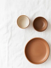 Three small ceramic bowls arranged on a white surface. the bowls are of different sizes and shapes, with the largest one in the center and two smaller ones on either side.