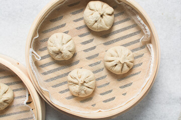 Overhead view of chicken bao in a bamboo steamer, top view of baozi in a steamer, process of making homemade baozi