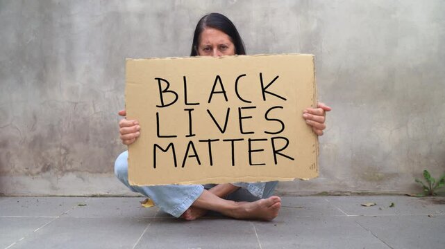 A Woman Protesting While Holding Placard With Black Lives Matter Sign. Close-up Shot