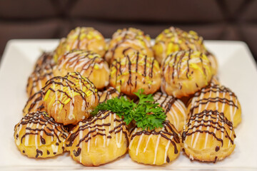The plate showcases cream puffs drizzled with chocolate and white icing, garnished with parsley. Perfectly arranged, the dessert looks irresistibly appetizing, ideal for food lovers