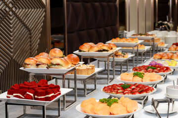 The image shows a buffet table with assorted dishes like sandwiches, cakes, and fruits, elegantly arranged on white plates and tiered stands. The setup is classy and visually appealing