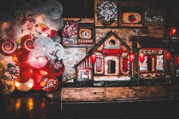 A captivating scene featuring colorful traditional Asian umbrellas, meticulously arranged around a wooden structure. Illuminated with soft, vibrant lighting, the setting exudes cultural artistry