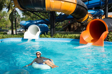 Thai women swimming and playing slider water and water ring in pool at outdoor of water park in...