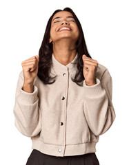 Young filipino woman celebrating a victory, passion and enthusiasm, happy expression.