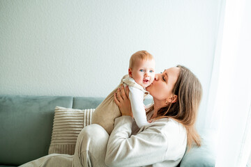 Happy mother holding her little son 9 months in her arms at home.