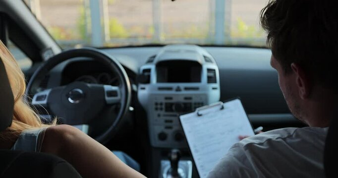 Car instructor teaches a young woman how to drive. Teaching the rules of the road and driving a vehicle. Driver courses, exam and people concept.