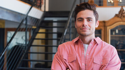 Portrait Of Smiling Male Owner Of Fashion Store Standing In Front Of Clothing Display