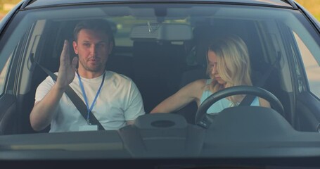 Woman and driving school instructor talking in car. Instructor teaches a young woman how to drive. Driver courses, exam and people concept.