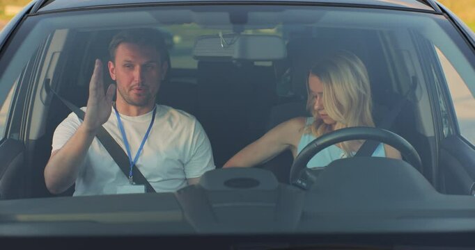 Woman and driving school instructor talking in car. Instructor teaches a young woman how to drive. Driver courses, exam and people concept.