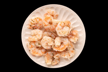 Seafood salad, shrimp with garlic on a ceramic plate isolated on a black background, close-up, top view.