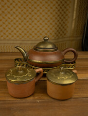 Terracotta teapot with brass accents wooden surface no people warm lighting highlight traditional...