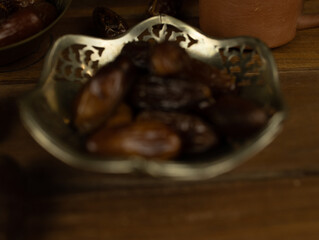 Dates in brass bowl wooden surface no people warm lighting traditional Middle Eastern setting