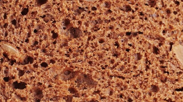 Sliced rye wholegrain bread on dark ructic macro closeup, bread with cereals.