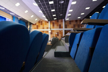 The blue-colored chairs face the stage in a row, illuminated by spectacular white lighting. The atmosphere suggests anticipation of an upcoming event or performance. High quality photo