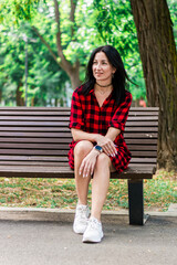 Brunette girl in a red checkered dress in the park