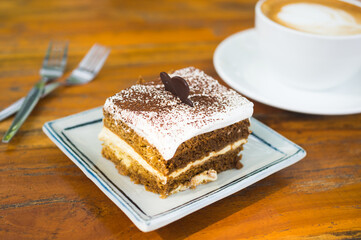 Tiramisu cake on dish with coffee cup.