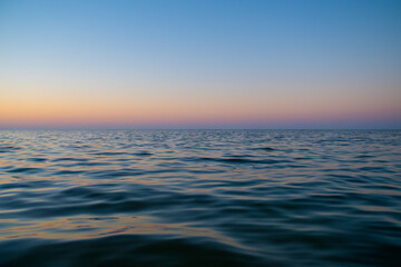 Fototapeta premium Sunset over sea background with empty space for text. View at water level.